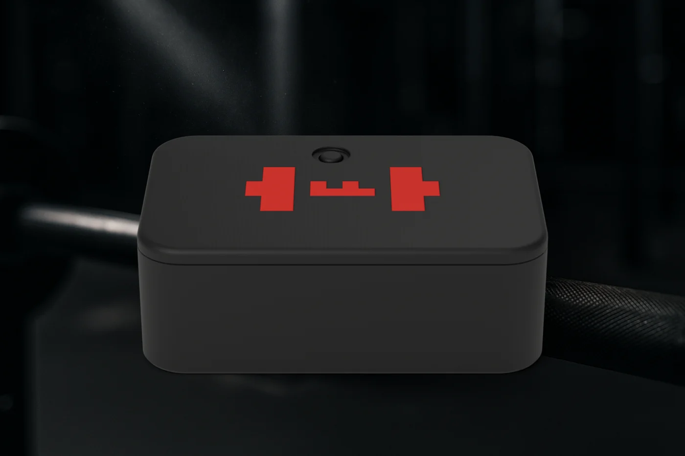 The TEMPO ANVIL on a barbell in a dark gym: a small black printed puck with rounded corners, a red TEMPO barbell mark on its lid and a single button