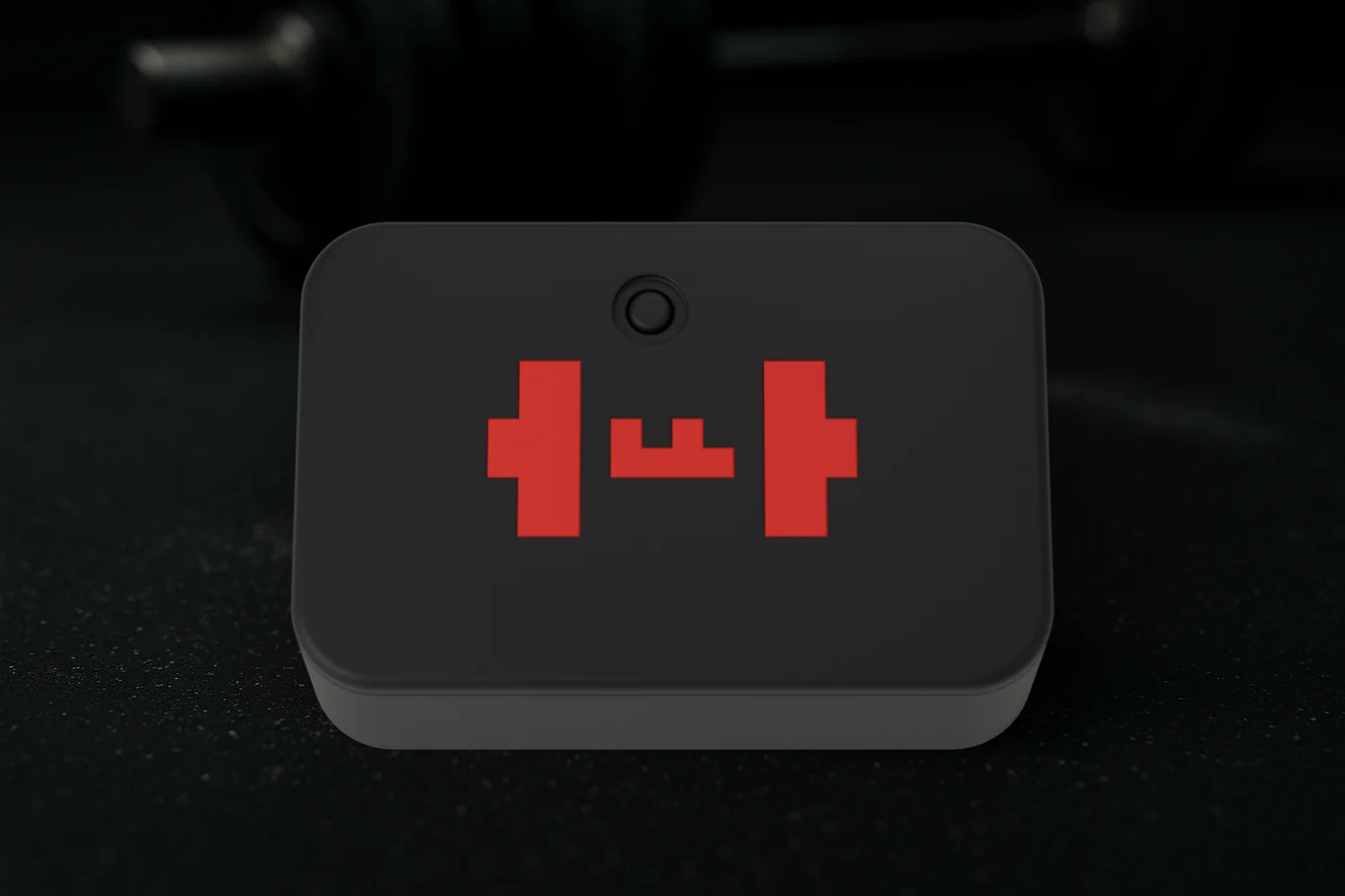 The TEMPO ANVIL from above on a rubber gym floor: the black lid with the red TEMPO barbell mark set flush into it and the button near one end